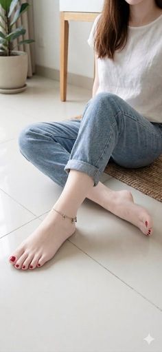 Person with bare feet and red nail polish wearing jeans and a white t-shirt