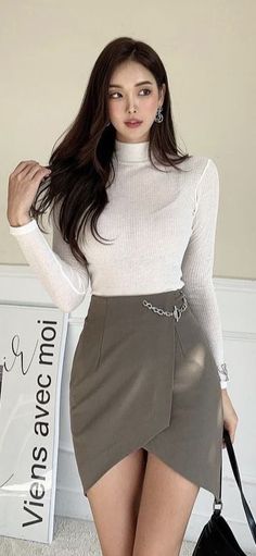 Woman with long dark hair wearing a white turtleneck and a mini skirt indoors