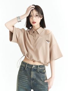 Woman with short hair wearing a cropped top and jeans, posing in a studio