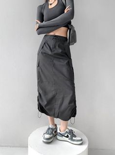 Person in a dark gray long sleeve crop top and cargo skirt with sneakers