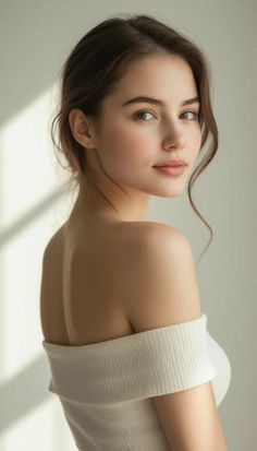 Woman in an off-shoulder top looking over her shoulder with soft lighting
