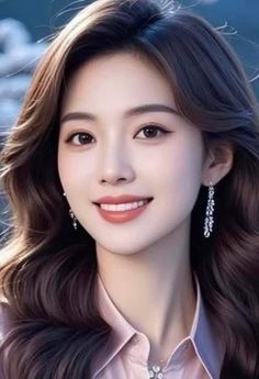 Woman with long wavy hair and earrings smiling in a pink shirt