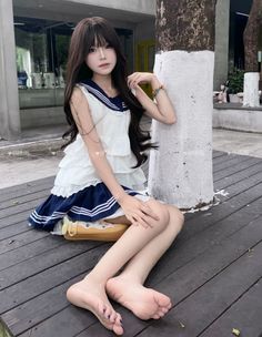 Woman with long dark hair in a sailor dress sitting on a wooden deck