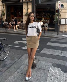 Woman in a white t-shirt and mini skirt standing on a city street