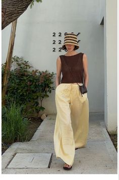 Woman in a straw hat and wide leg pants walking outdoors
