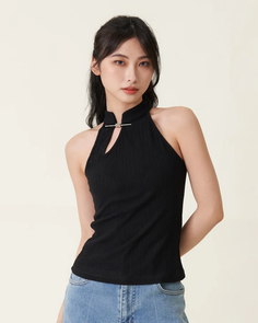 Woman with black hair wearing a black halter top and jeans in a studio shot