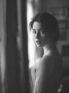 Woman with short hair in a ribbed top looking over her shoulder