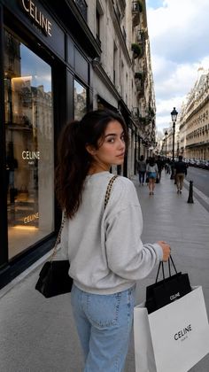 Woman with a ponytail walking on a city street with shopping bags