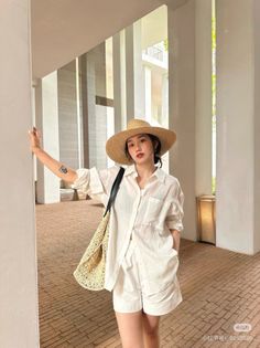 Woman in a straw hat and white outfit posing outdoors