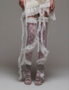 Person in a white ruffled dress with lace stockings and strappy sandals
