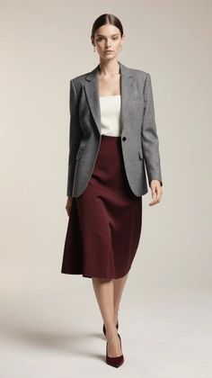 Woman in a gray blazer and maroon skirt walking in a studio