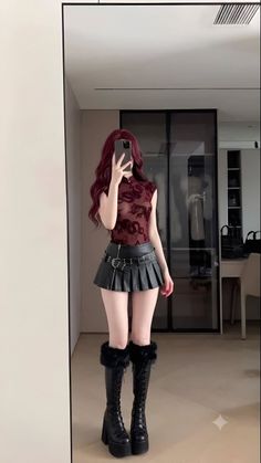 Woman with long red hair in a sheer top and mini skirt taking a mirror selfie