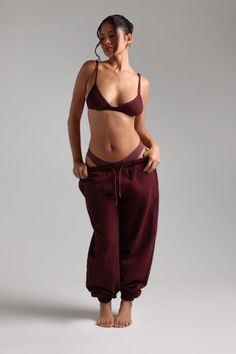 Woman in a maroon bra and sweatpants in a studio setting