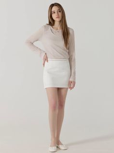 Woman with long hair wearing a white mini skirt and long sleeve top on a white background