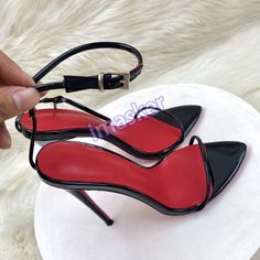Pair of black patent leather high heels with red soles and ankle straps