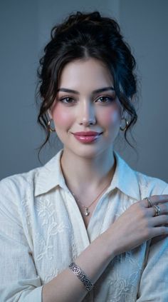 Woman with dark hair in an updo wearing a white shirt and jewelry