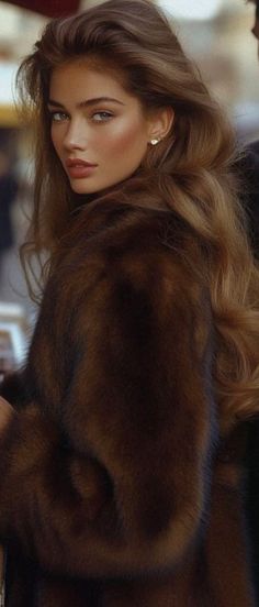 Woman with long brown hair wearing a fur coat and earrings