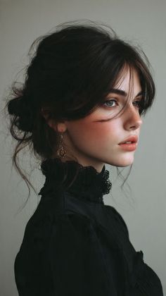 Woman with dark hair in an updo wearing a black top with a lace collar