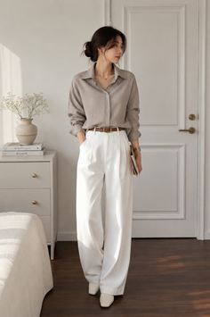 Woman in a striped shirt and white pants standing in a minimalist room