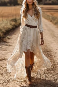 Woman in a white dress and cowboy boots walking on a dirt road