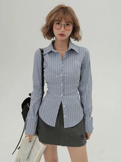 Woman with short hair and glasses wearing a striped shirt and mini skirt