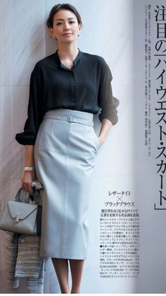 Woman in a black blouse and light gray pencil skirt holding a handbag