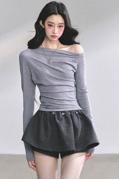 Woman with long black hair wearing an off-shoulder top and mini skirt