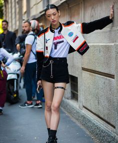 Woman in a racing jacket and black shorts with a spiked garter on a street