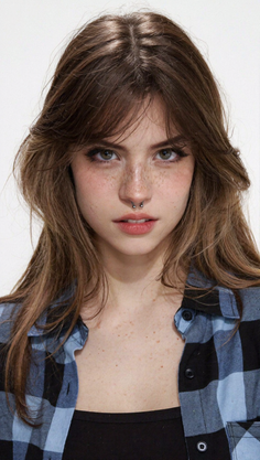 Woman with long hair, freckles, and a septum piercing wearing a plaid shirt