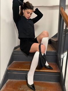 Young woman in a black jacket and white socks sitting on wooden stairs
