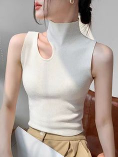 Woman in a white sleeveless top with a high neck and cut-out detail