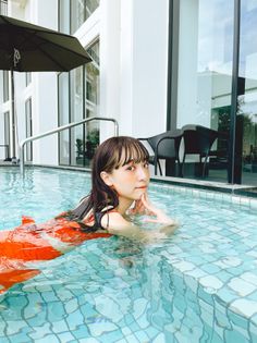 Woman with long hair in an orange swimsuit in a swimming pool