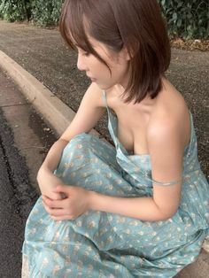 Woman with short hair in a floral dress sitting outdoors