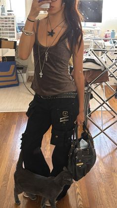 Person in a brown tank top and black cargo pants with a gray cat indoors
