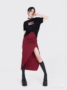 Woman in a black t-shirt and red skirt with platform boots on a white background
