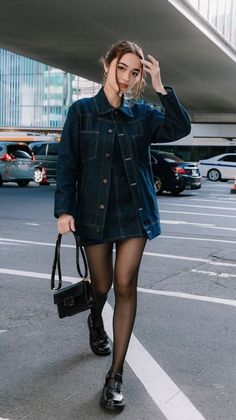 Woman in a denim jacket and mini skirt walking on a city street