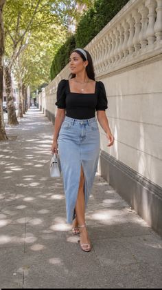 Woman in a black top and denim skirt walking on a sunny street