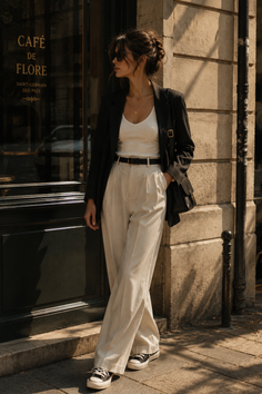 Woman in a blazer and wide leg pants standing outside a cafe