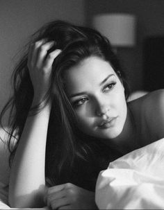 Woman with long dark hair in a black and white bedroom portrait