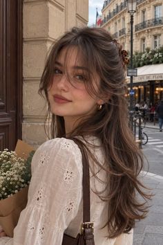 Woman with long brown hair and a white blouse on a street