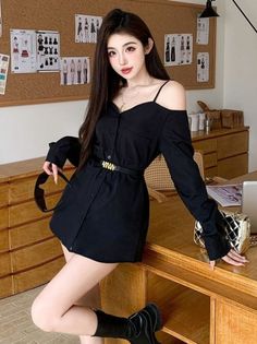 Woman in a black off-shoulder dress and boots posing indoors