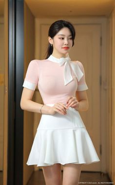 Woman in a pink top and white skirt with a ponytail indoors