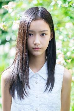 Young girl with long dark hair wearing a white collared shirt outdoors