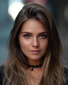 Woman with long brown hair and a choker looking directly at the camera
