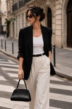Woman in a black blazer and white pants walking on a city street