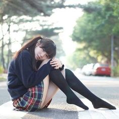 Young woman in a school uniform sitting on a street