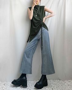 Person in a dark green top and wide leg jeans with platform boots