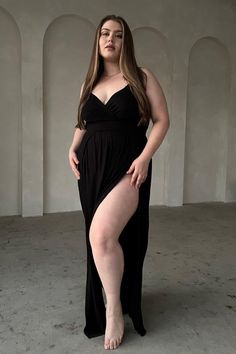 Woman in a black dress with a high slit posing indoors