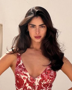 Woman with long dark hair wearing a red and white floral top