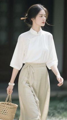 Woman in traditional white top and light skirt holding a woven bag